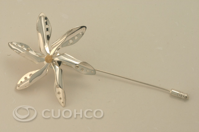Sterling silver brooch in the shape of a rotary pinwheel with gold central motif in diamond finish