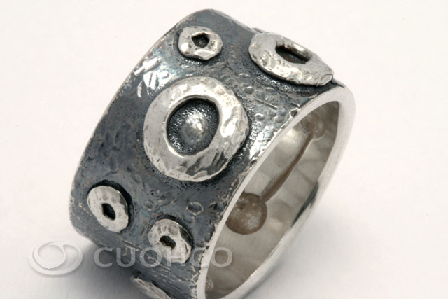 Wide sterling silver ring with shapes and textures that simulate lunar craters