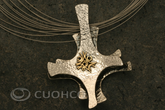 Sterling silver pendant with overlapping motifs at different heights with hammered texture and a central gold grid