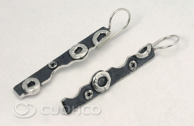 Long sterling silver earrings of uneven inner edges with shapes and textures that simulate lunar craters